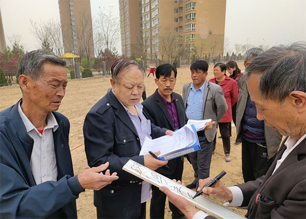 新府山社区组织易地搬迁党员、楼栋长为易地搬迁报名种植的脱贫户划分土地.jpg